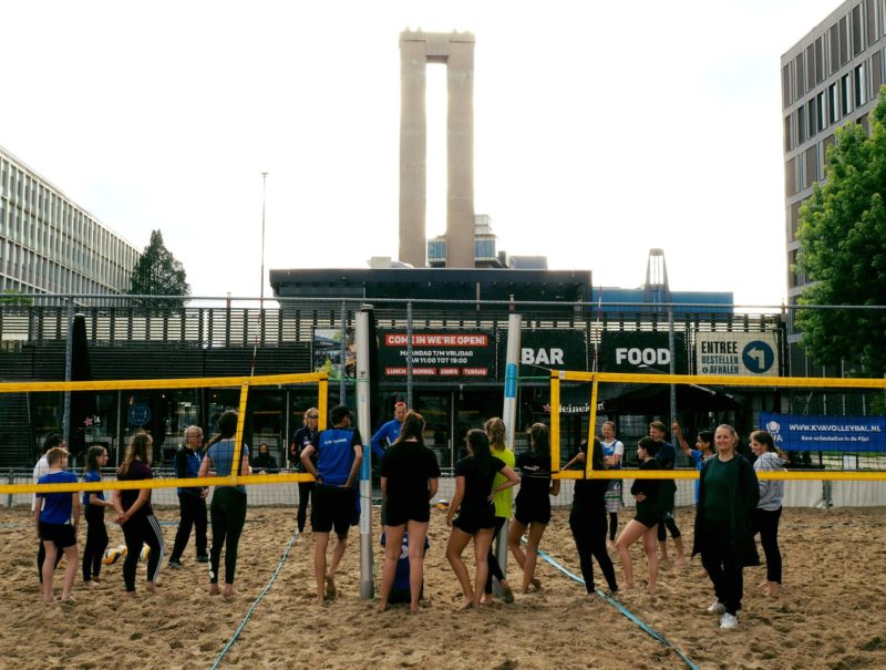 Jeugdleden staan in een cirkel tijdens de beachvolleybaltraining op de VU Campus.